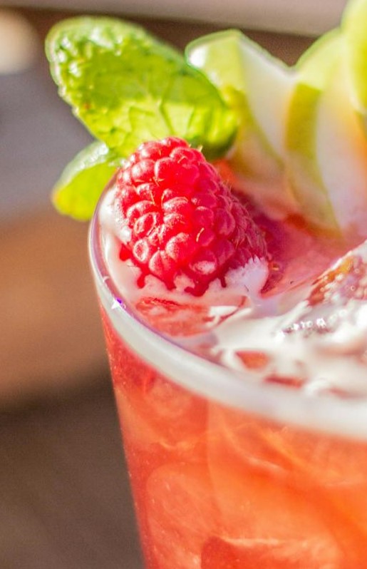 icy cocktail topped with fresh raspberry and mint garnish